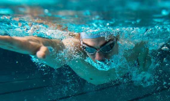 Ein Schwimmer mit Schwimmbrille und Badekappe gleitet im Zieselsmaar-Becken im Freistil unter Wasser dahin, die Arme nach vorne ausgestreckt, und genießt die Freizeit in vollen Zügen.