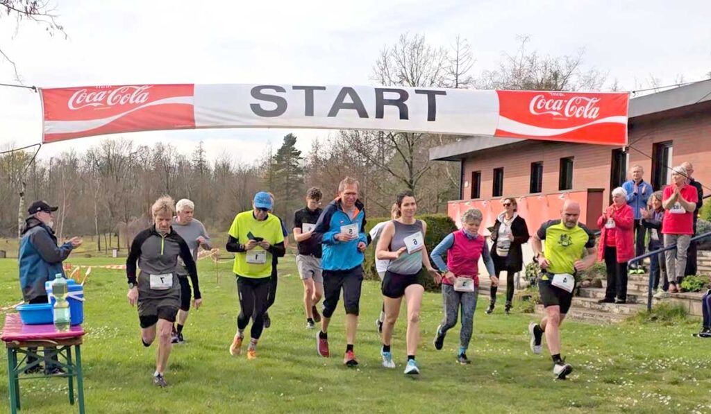 Eine Gruppe von Läufern startet unter einem „START“-Banner auf der Wiese in Zieselsmaar, während die Zuschauer in der Nähe ihre Freizeit genießen und dem Geschehen zuschauen.