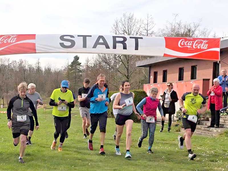 Eine Gruppe von Läufern startet bei einem Freizeitlauf unter einem Banner mit der Aufschrift „START“.